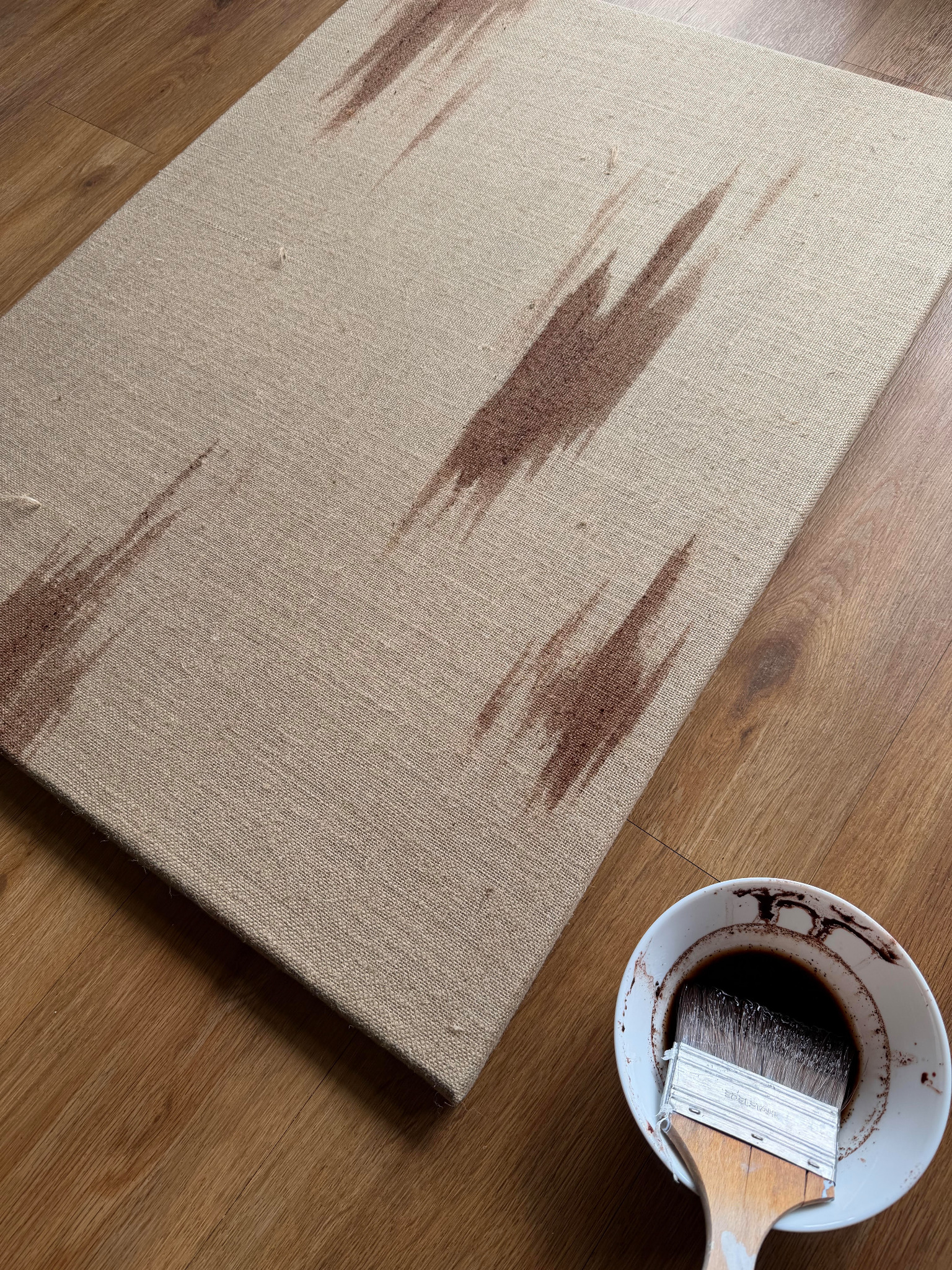 Leinwand mit erdigen Farbspuren und Schale mit dunklem Naturfarbstoff