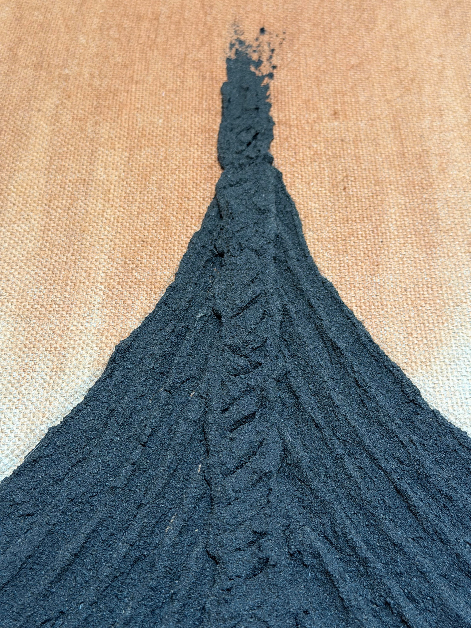 Detailaufnahme einer schwarzen reliefartigen Schiffsform auf naturbelassener Leinwand
