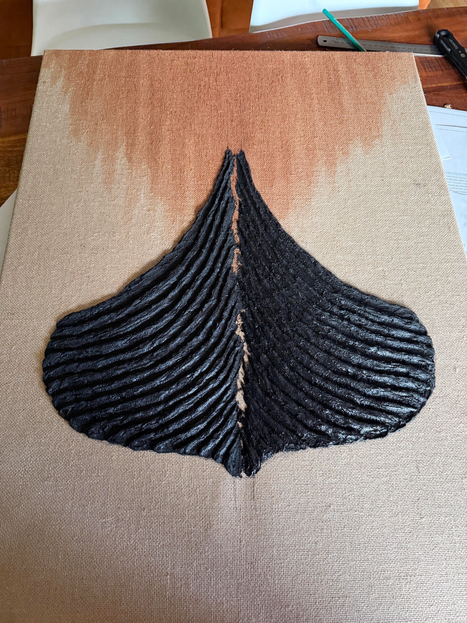 Schwarzes Reliefwerk in Schiffsform auf naturbelassener Leinwand, im Atelier fotografiert